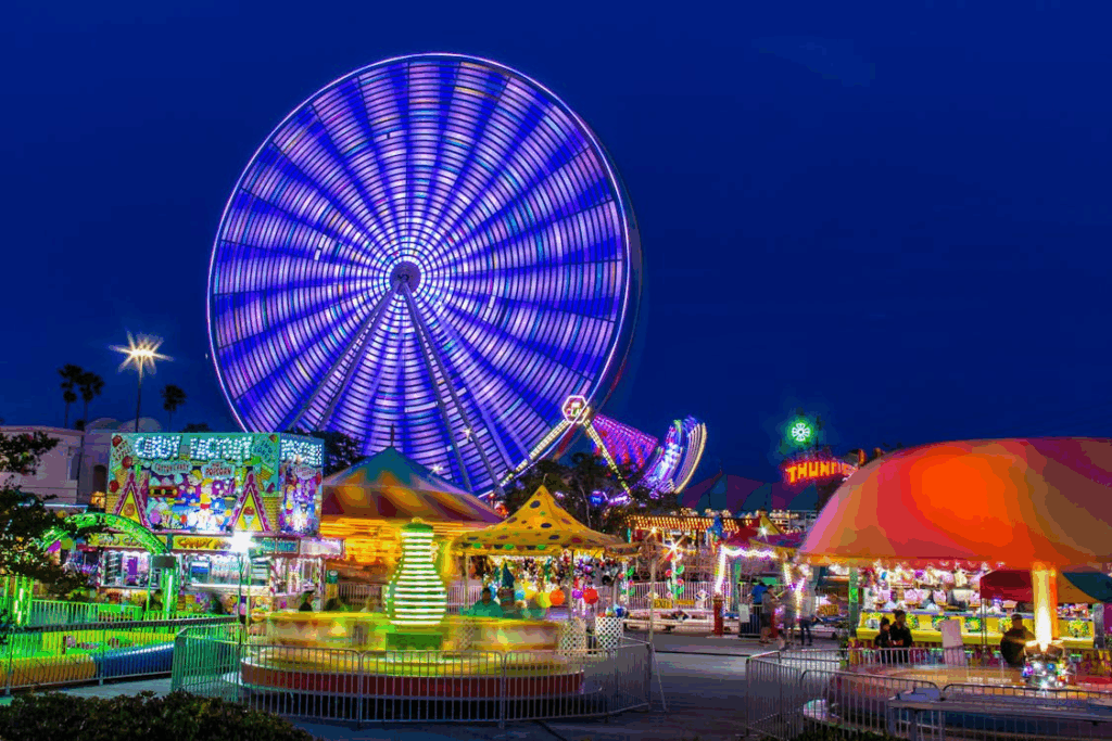 Nighttime theme park with bright rides and Ferris wheel, representing credit union theme park discounts.
