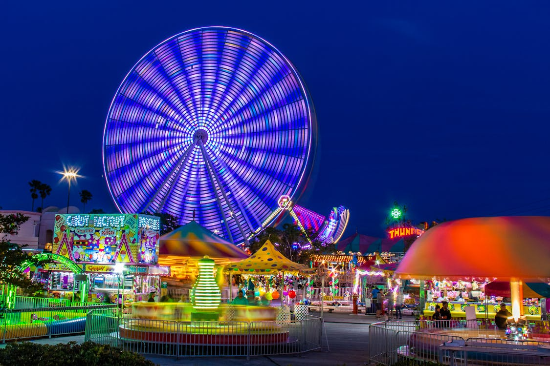 Nighttime theme park with bright rides and Ferris wheel, representing credit union theme park discounts.
