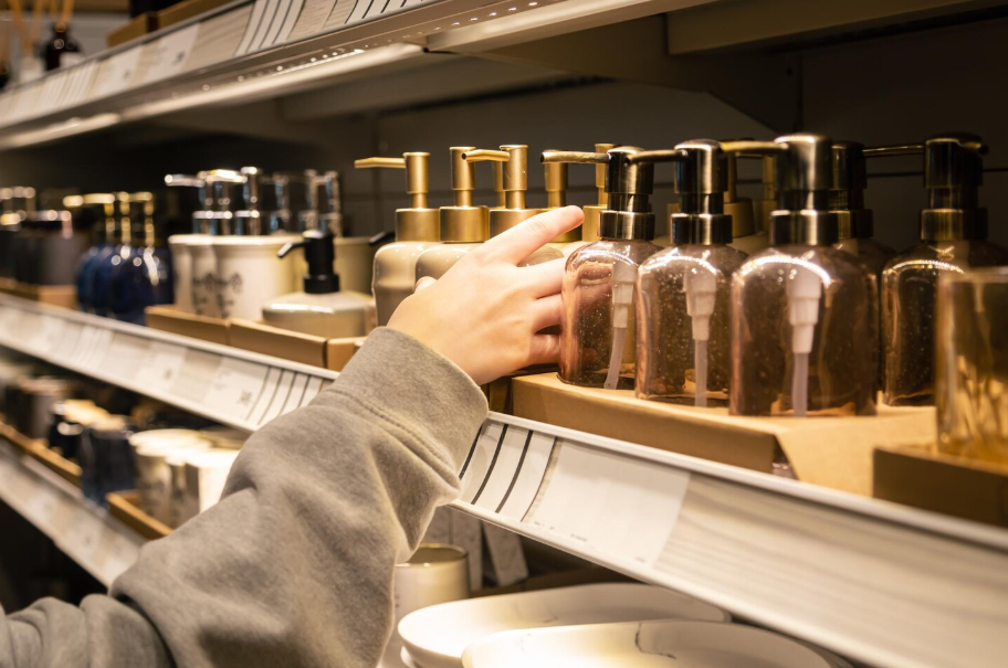 Hand choosing affordable home goods alternative bottles on a store shelf.